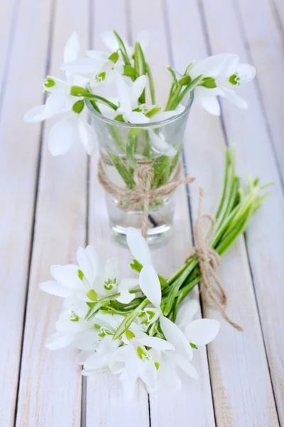 Beaux bouquets de gouttes de neige dans des vases sur fond de bois — Photo