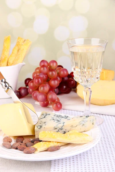 Assorted cheese plate, cocoa beans and grape on tablecloth background, close-up — Stock Photo, Image