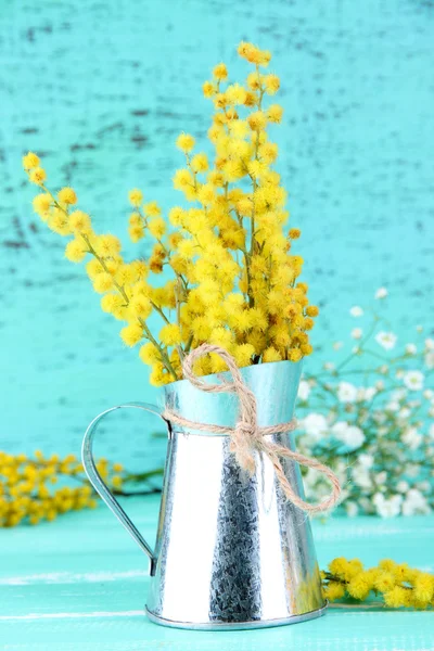 Гілочки квітів мімози у вазі на синьому дерев'яному столі — стокове фото