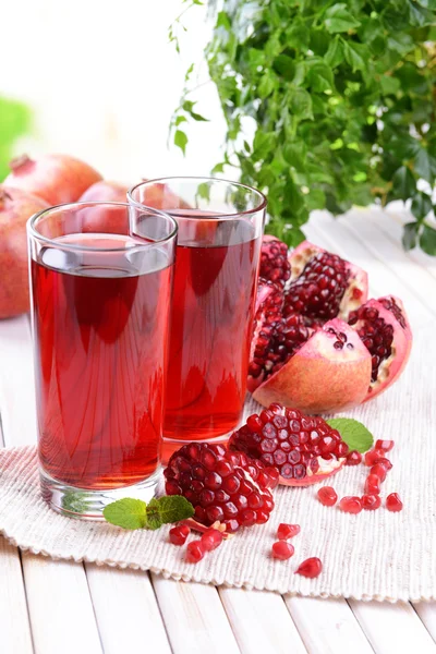 Melograni maturi con succo sul tavolo su sfondo chiaro — Foto Stock