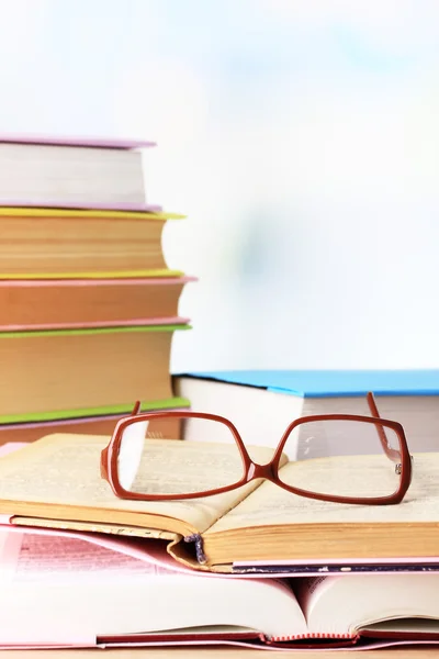 Sammansättning med glasögon och böcker, på bord, på ljus bakgrund — Stockfoto