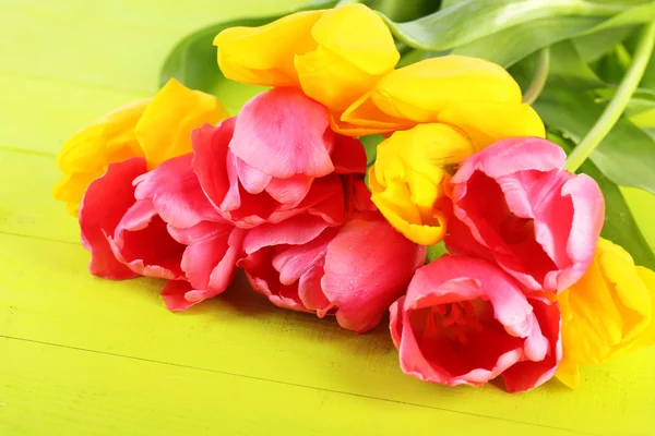 Różowe i żółte tulipany na drewnianym stole — Zdjęcie stockowe