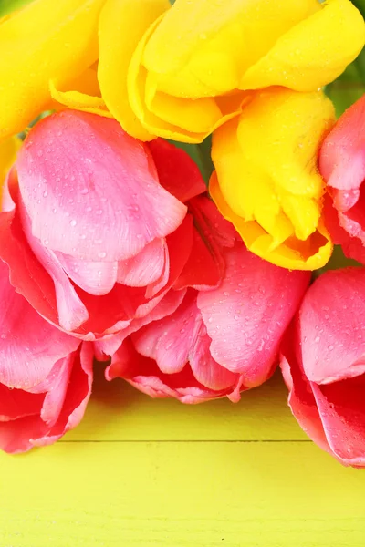 Rosa und gelbe Tulpen auf Holztisch — Stockfoto