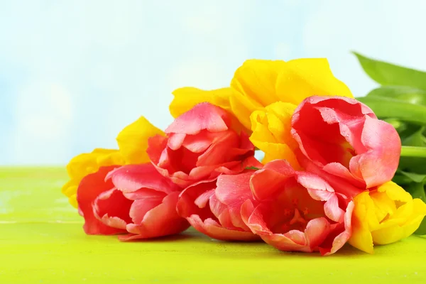 Tulipani rosa e gialli su tavola di legno su sfondo naturale — Foto Stock