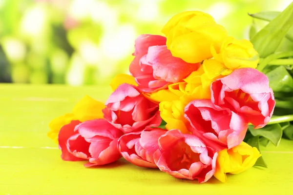 Pink and yellow tulips on wooden table on natural background — Stock Photo, Image