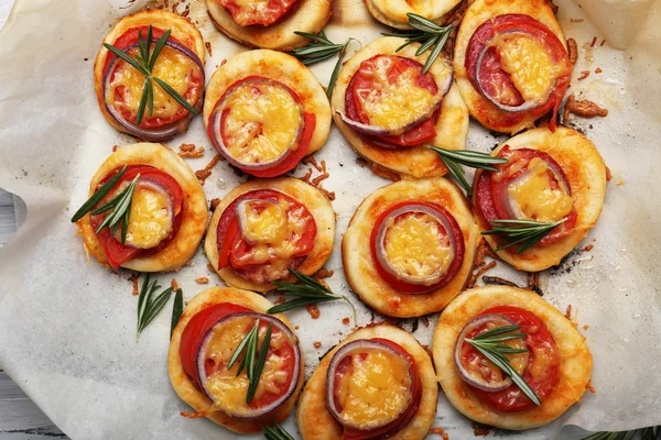 Pequeñas pizzas sobre papel de hornear de cerca — Foto de Stock