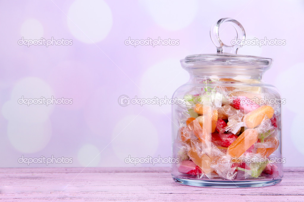 Tasty candies in jar on table on bright background