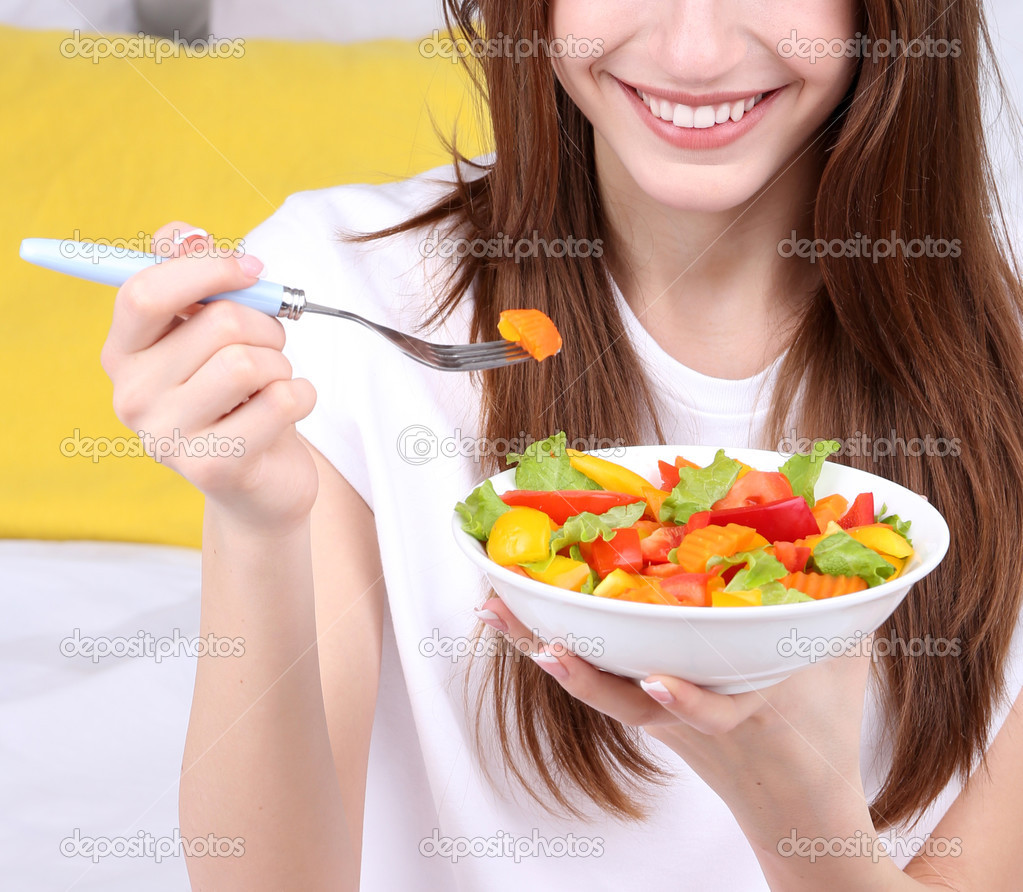 Young beautiful woman on bed with healthy salad