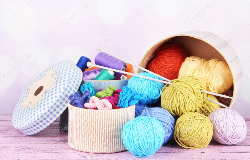 Decorative boxes with colorful skeins of thread on table on bright background