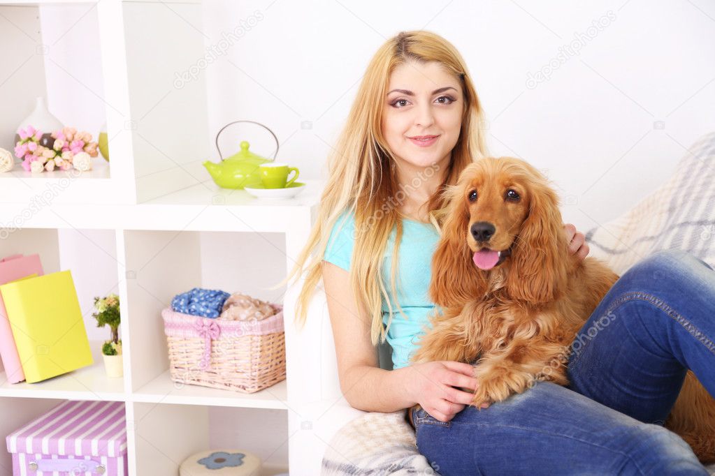 Beautiful young woman with cocker spaniel on couch in room