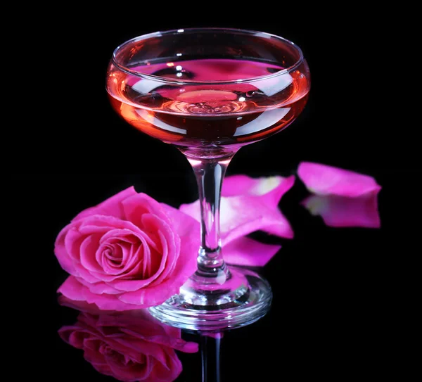 Komposition mit rosa Sekt im Glas und Rose isoliert auf schwarz — Stockfoto