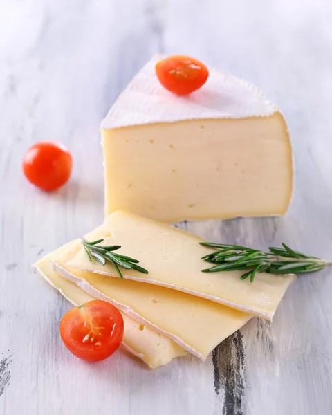 Chutný sýr camembert s rajčaty a rozmarýnem na dřevěný stůl — Stock fotografie