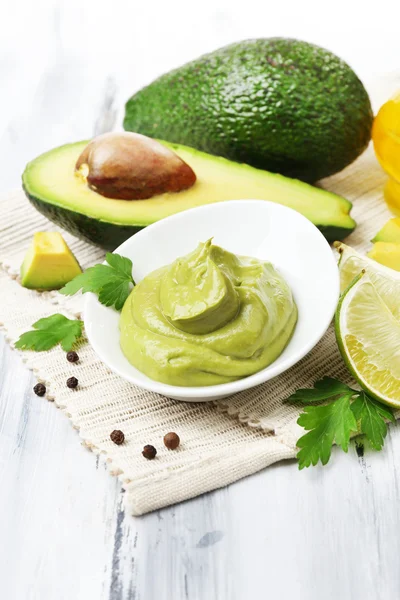 Fresh guacamole in bowl on wooden table — Stock Photo, Image