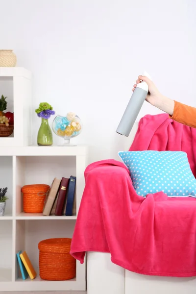 Sprayed air freshener in hand on home interior background — Stock Photo, Image