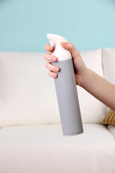 Sprayed air freshener in hand on sofa background — Stock Photo, Image