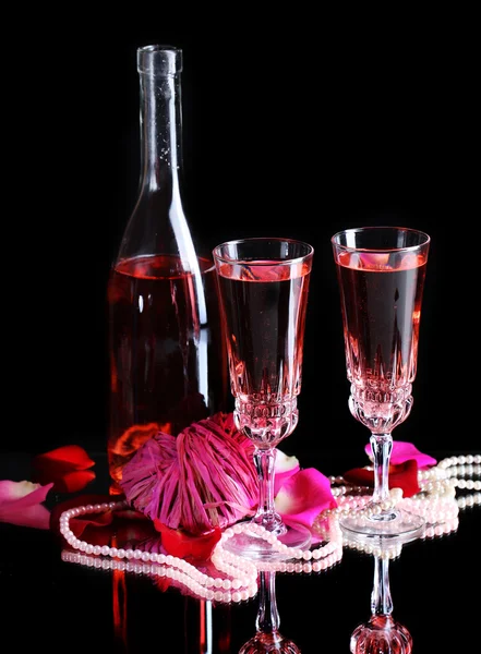 Composition with pink  wine in glasses, bottle  and  roses isolated on black background Stock Picture