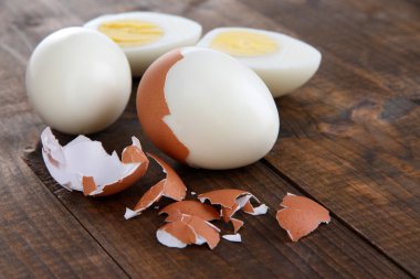 Peeled boiled egg on wooden background clipart