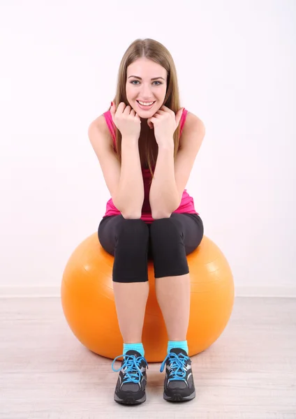 Joven hermosa chica de fitness haciendo ejercicio con bola naranja en el gimnasio —  Fotos de Stock