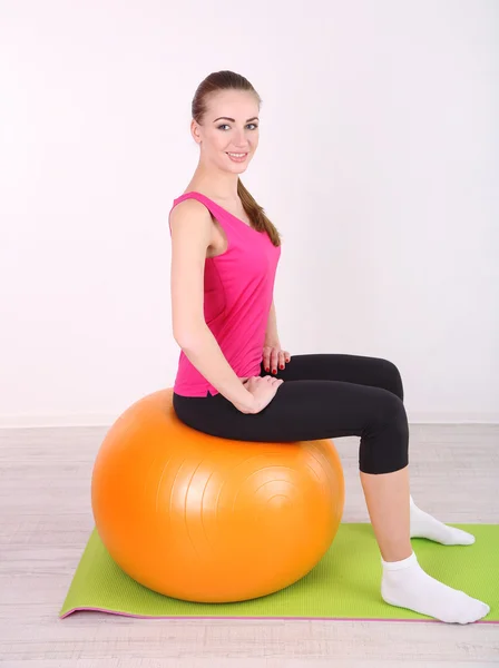Jovem bela menina fitness exercitando com bola laranja no ginásio — Fotografia de Stock