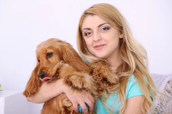 Beautiful young woman with cocker spaniel on couch in room — Stock Photo, Image