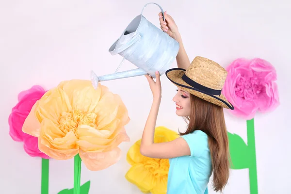 Beautiful young woman watering flower on decorative background — Stock Photo, Image