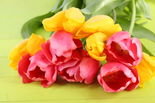 Tulipanes rosados y amarillos sobre mesa de madera —  Fotos de Stock