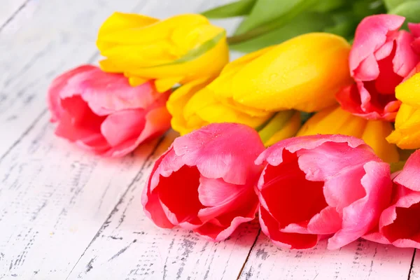 Tulipanes rosados y amarillos sobre mesa de madera —  Fotos de Stock