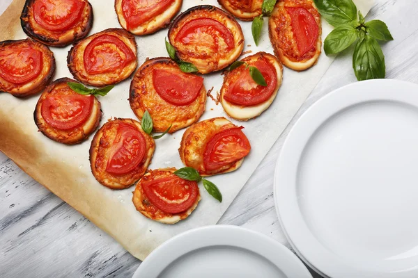 Små pizzor på bakplåtspapper på nära håll — Stockfoto