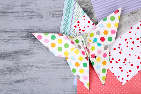 Origami motýla a barevné papíry na dřevěný stůl — Stock fotografie
