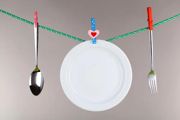 Tableware dried on rope on grey background — Stock Photo, Image