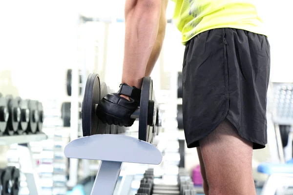 Man met halters op gym achtergrond close-up — Stockfoto