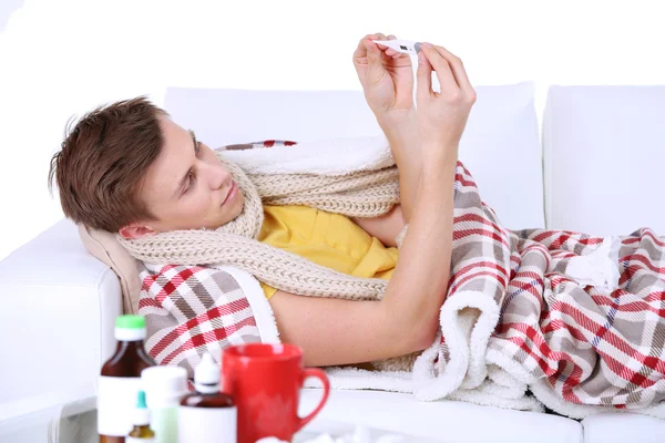 Guy wrapped in plaid lies on sofa is ill — Stock Photo, Image