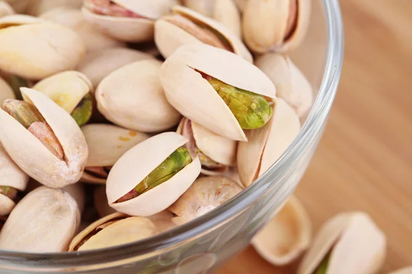 Pistachio nuts in glass bowl on wooden background — Stock Photo, Image