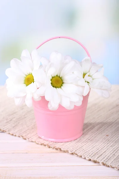 Lindas flores de crisântemo em balde na mesa no fundo claro — Fotografia de Stock