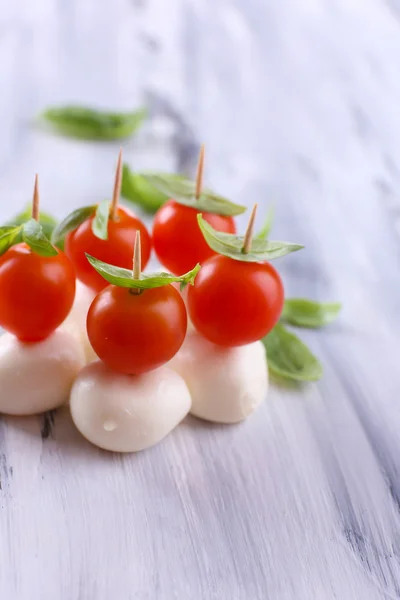 Tasty mozzarella cheese with basil and tomatoes, on wooden table — Stock Photo, Image