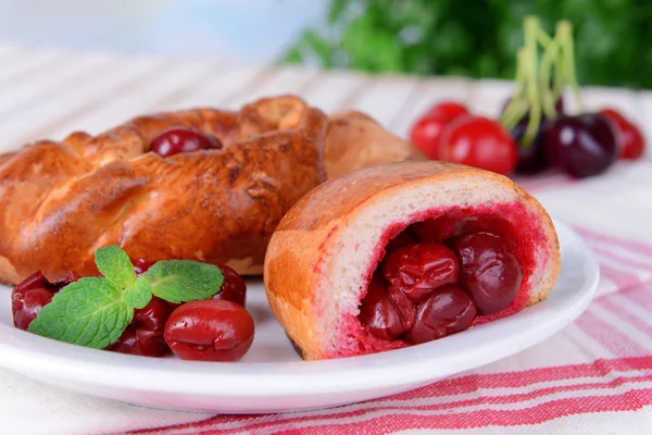 Fresh baked pasties with cherry on plate on table close-up — Stock Photo, Image