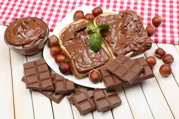Pâine cu alune dulci de ciocolată răspândită pe fundal din lemn — Fotografie, imagine de stoc