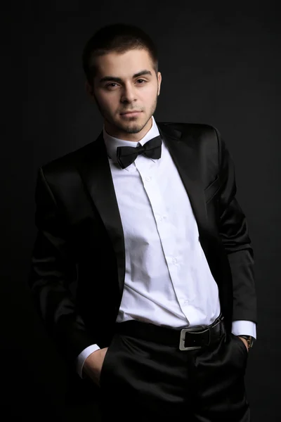 Handsome young man in suit on dark background — Stock Photo, Image