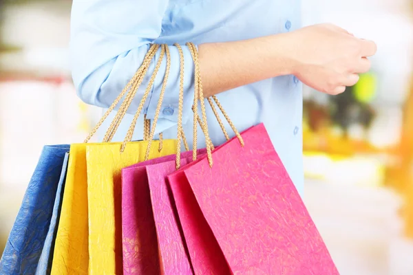 Young woman holding colorful shopping bags in  her hand, on bright background — Stock Photo, Image