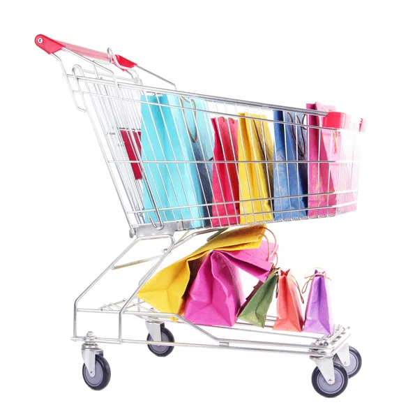 Barevné tašky v nákupním vozíku, izolované na bílém — Stock fotografie