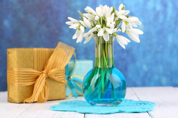 Beaux gouttes de neige dans un vase, sur une table en bois sur fond lumineux — Photo