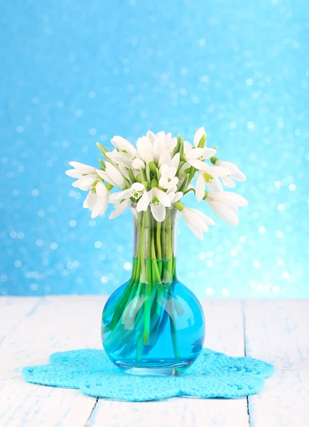 Beaux gouttes de neige dans un vase, sur une table en bois sur fond lumineux — Photo