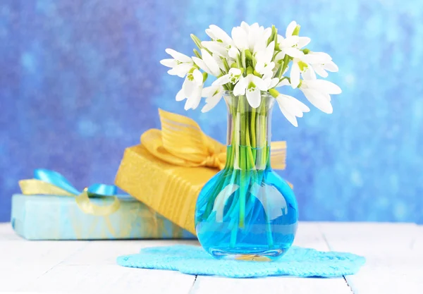 美丽的雪莲花，插在花瓶里，在明亮的背景上木制的桌子上 — 图库照片