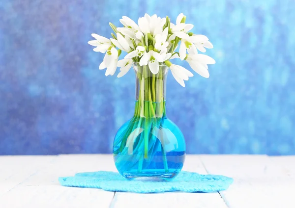 Beautiful snowdrops in vase, on wooden table on bright background — Stock Photo, Image