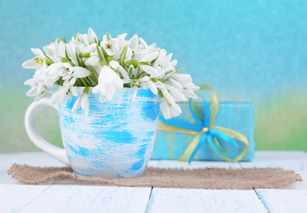 Beautiful snowdrops in vase, on wooden table on bright background — Stock Photo, Image