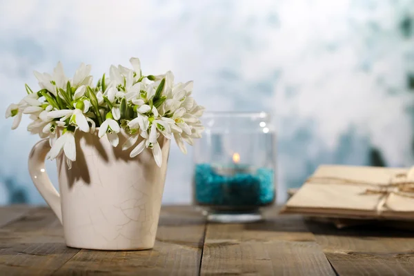 Composition avec de beaux gouttes de neige dans un vase, une bougie, de vieilles lettres et des photos sur une table en bois sur fond lumineux — Photo