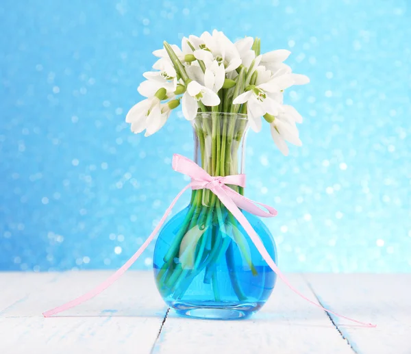 Krásný sněženky v váza, na dřevěný stůl na světlé pozadí — Stock fotografie
