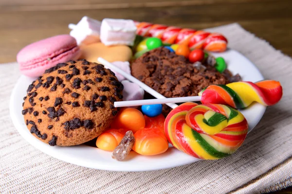 Различные сладости на тарелке на столе крупным планом — стоковое фото