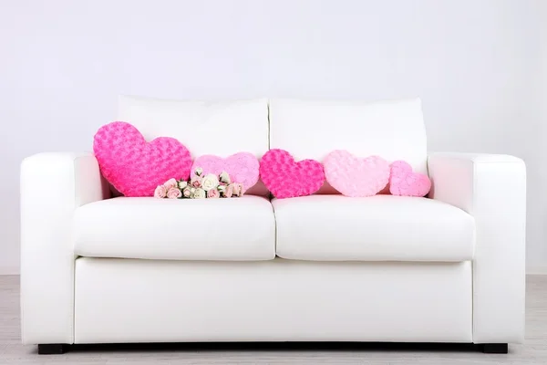 Pink hearts shaped pillow and  flowers on white sofa — Stock Photo, Image