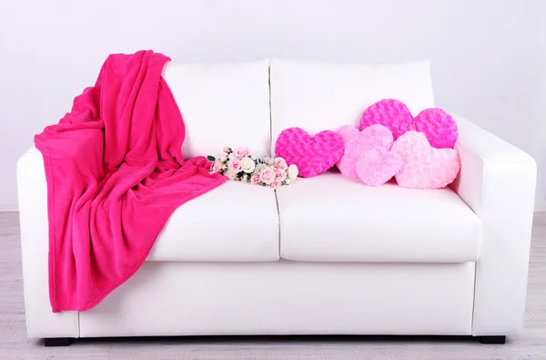 Pink hearts shaped pillows and flowers on white sofa — Stock Photo, Image